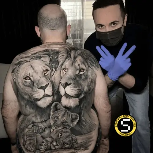 Gabriele Pellerone con un full back composto da leonessa, leone e due cuccioli, tatuaggio svolto per copertura di un tatuaggio precedente. occhi gialli 